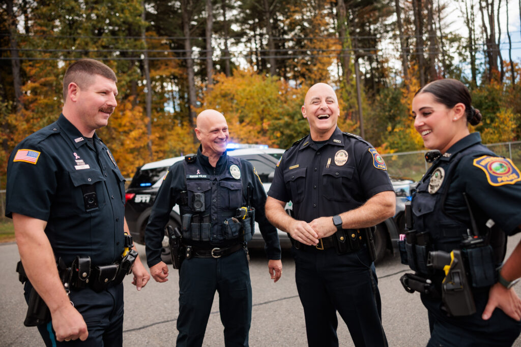 Four Hudson police officers stand laughing.