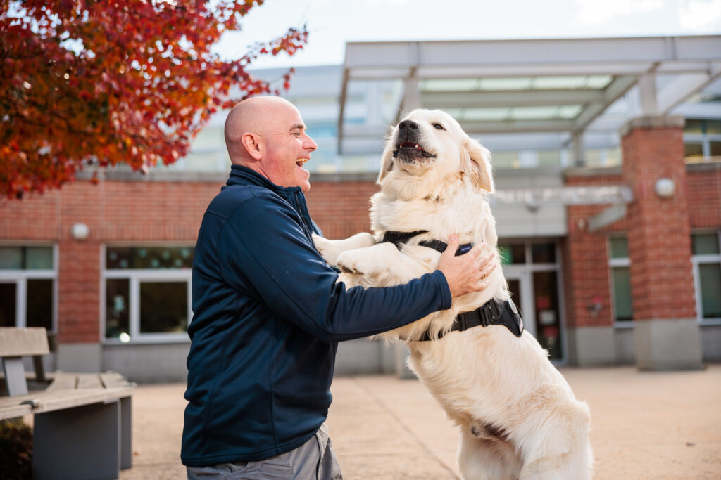 Hudson Police School Resource Officer pets white golden retreiver.