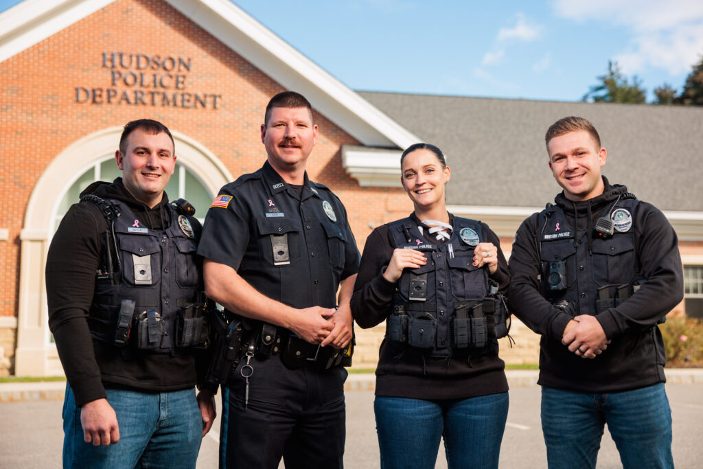Four police officers standing in front of the Hudson Police headquarters.